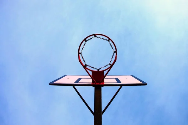 Antiguo tablero de baloncesto descuidado con aro oxidado sobre la cancha de la calle. Cielo azul — Foto de Stock