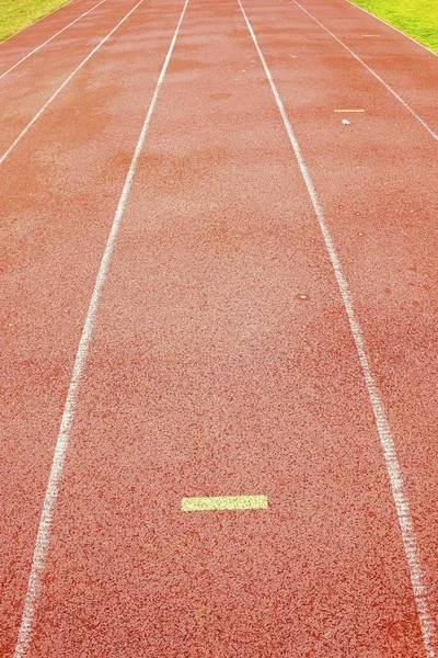 Marcas amarillas. Líneas blancas y textura de la pista de carreras, pista roja, en el estadio al aire libre — Foto de Stock