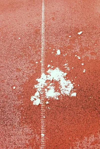 Havas földön. Fehér vonalak és a textúra a futó versenypálya, piros versenypálya, a szabadtéri stadionban — Stock Fotó