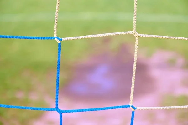 Vista do portão de futebol para a água e mude no campo de futebol pobre. Gramado danificado no estádio de futebol ao ar livre — Fotografia de Stock