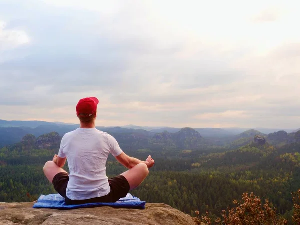 Solitario sentado practicando Yoga posan en el pico rocoso. El hombre dentro de la mañana brumosa hacer meditación —  Fotos de Stock