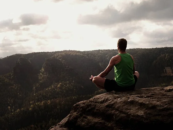 Hombre en la cima de la montaña en pose de yoga. Ejercicio yoga en el borde con una vista impresionante —  Fotos de Stock