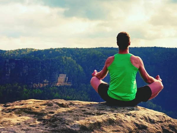 Hombre en la cima de la montaña en pose de yoga. Ejercicio yoga en el borde con una vista impresionante —  Fotos de Stock