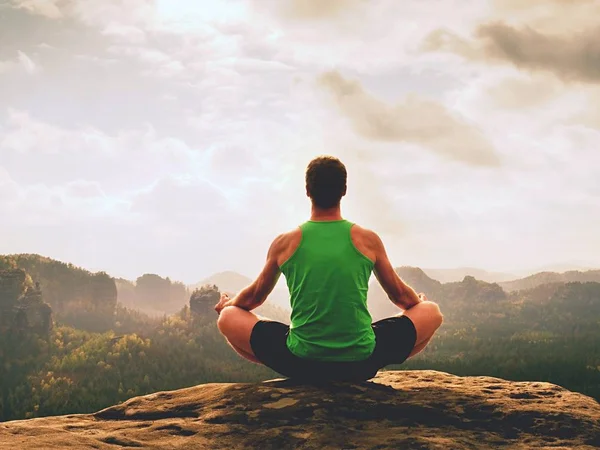 Solo el hombre está haciendo la postura del yoga en el pico de las rocas dentro de la mañana brumosa. Hombre de mediana edad practicando yoga — Foto de Stock