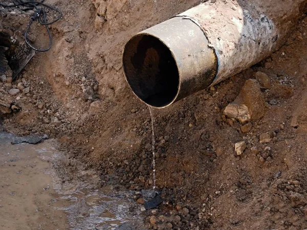 Rostiges altes Eisenrohr, aus dem klares Wasser fließt. Abwasserrohr — Stockfoto