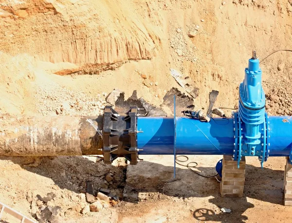 Grandes válvulas de portão industriais em dutos com grande roda de mão. tubulação de água da bebida reparada no furo escavado . — Fotografia de Stock
