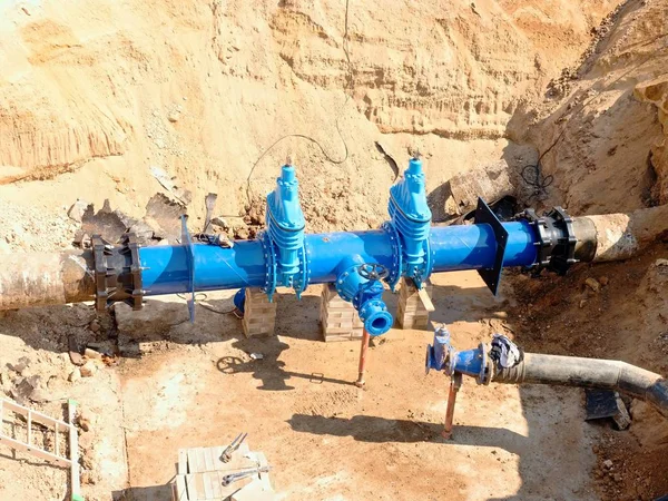 Válvulas de compuerta industriales grandes en tuberías con rueda de mano grande. Tubería de agua potable reparada en un agujero cavado . — Foto de Stock