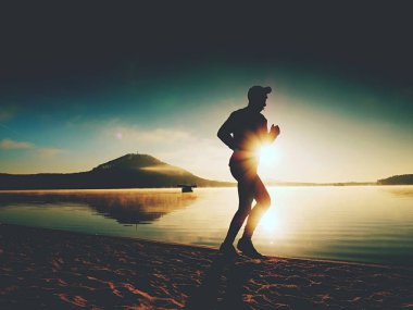 Uzun boylu deniz kıyısında sabah koşan adam uygun. Sağlıklı erkek sahilde koşu.