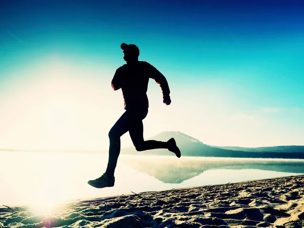 Hombre alto corriendo a lo largo de la orilla del mar en la mañana. Jogging masculino saludable en la playa . —  Fotos de Stock