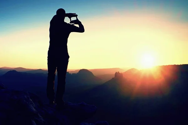 Турист делает раму с ладонями и пальцами на обеих руках. Прогулка по скалистой скале, рассвет в скалистых горах . — стоковое фото