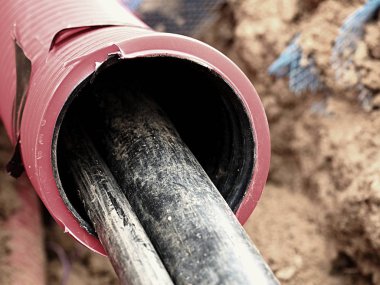 Koruyucu Hdpe boru içinde siyah kablolar ile hendek kazı. Metalik ve fiber optik kablo hatları.
