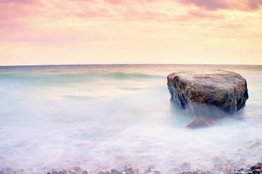 Denizde romantik atmosferi huzurlu sabah. Büyük kayalar pürüzsüz dalgalı denizden çıkmış. Pembe ufuk