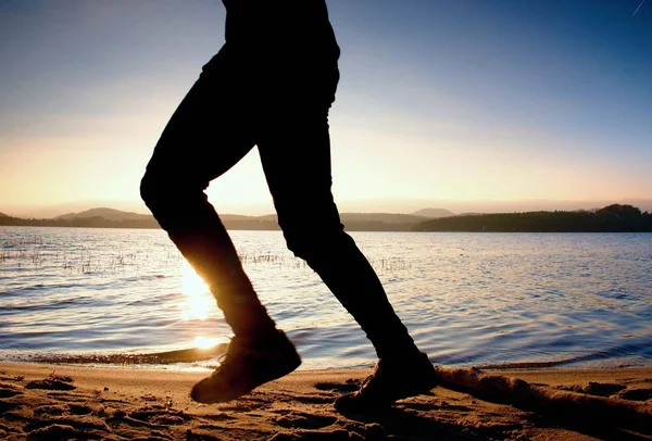 Silueta de hombre activo deportivo corriendo y ejercitándose en la playa al atardecer . — Foto de Stock