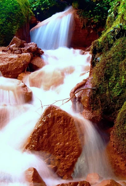 Cascades i snabb ström av mineralvatten. Röd järn (III) sediment på stora stenblock — Stockfoto