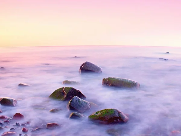 Sunset at rocky coast of sea. Low shutter speed for smooth water level and dreamy effect — Stock Photo, Image
