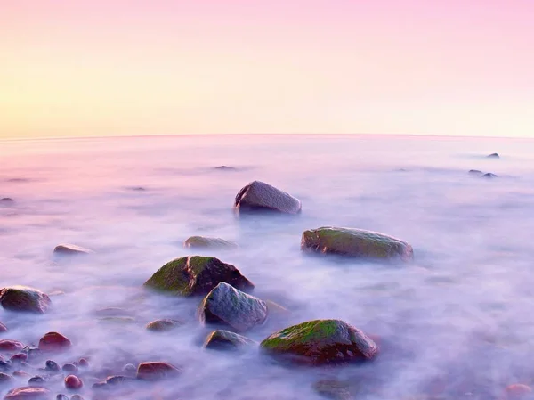 Puesta de sol en la costa rocosa del mar. Baja velocidad de obturación para un nivel de agua suave y efecto de ensueño —  Fotos de Stock