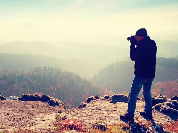 Photographer  on cliff. Nature photographer takes photos with mirror camera on peak