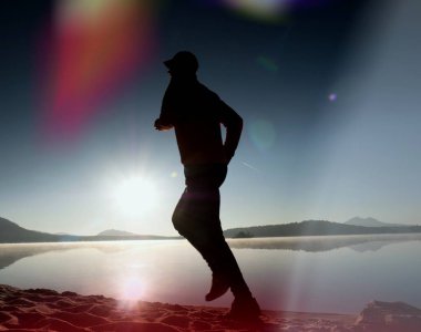  egzersiz ve göl kumsalda güneş doğarken uzanan bir adam. Sağlıklı bir yaşam tarzı. Yalnız genç fitness adam egzersiz sabah kumsalda