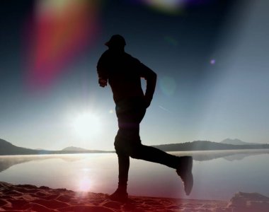  egzersiz ve göl kumsalda güneş doğarken uzanan bir adam. Sağlıklı bir yaşam tarzı. Yalnız genç fitness adam egzersiz sabah kumsalda