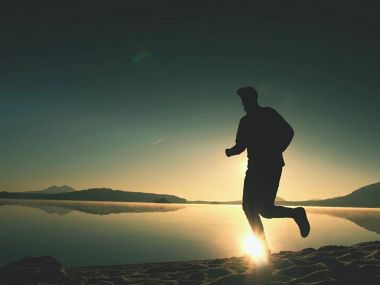  egzersiz ve göl kumsalda güneş doğarken uzanan bir adam. Sağlıklı bir yaşam tarzı. Yalnız genç fitness adam egzersiz sabah kumsalda