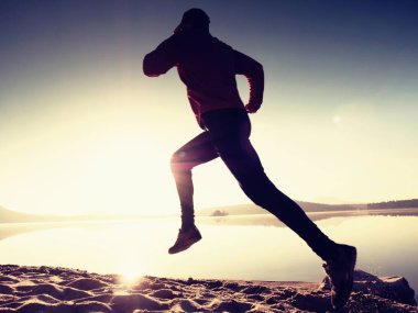Gündoğumu kıyıda çalışan etkin atlet runner silüeti. Sabah sağlıklı yaşam tarzı egzersiz