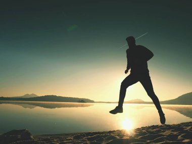  egzersiz ve göl kumsalda güneş doğarken uzanan bir adam. Sağlıklı bir yaşam tarzı. Yalnız genç fitness adam egzersiz sabah kumsalda