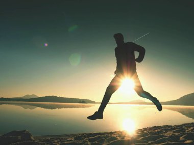  egzersiz ve göl kumsalda güneş doğarken uzanan bir adam. Sağlıklı bir yaşam tarzı. Yalnız genç fitness adam egzersiz sabah kumsalda