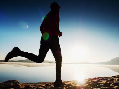  egzersiz ve göl kumsalda güneş doğarken uzanan bir adam. Sağlıklı bir yaşam tarzı. Yalnız genç fitness adam egzersiz sabah kumsalda