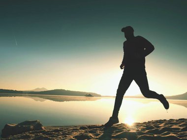  egzersiz ve göl kumsalda güneş doğarken uzanan bir adam. Sağlıklı bir yaşam tarzı. Yalnız genç fitness adam egzersiz sabah kumsalda