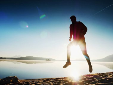  egzersiz ve göl kumsalda güneş doğarken uzanan bir adam. Sağlıklı bir yaşam tarzı. Yalnız genç fitness adam egzersiz sabah kumsalda