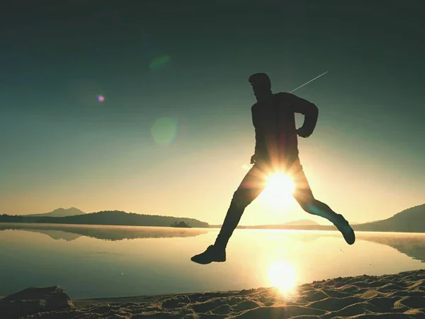 Homme exerçant et s'étendant sur la plage du lac au lever du soleil. Mode de vie sain. Seul jeune homme de fitness exercice à la plage du matin — Photo