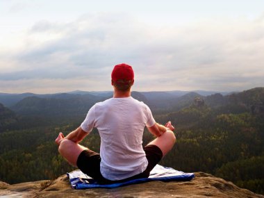 Yalnız adam pratik Yoga poz kayalık tepe üzerinde oturuyor. Adam puslu sabah içinde meditasyon yapmak 