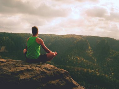 Adam içinde Lotus poz kayalık uçurum üzerinde meditasyon. Pratik Yoga taş kenarında sporcu 