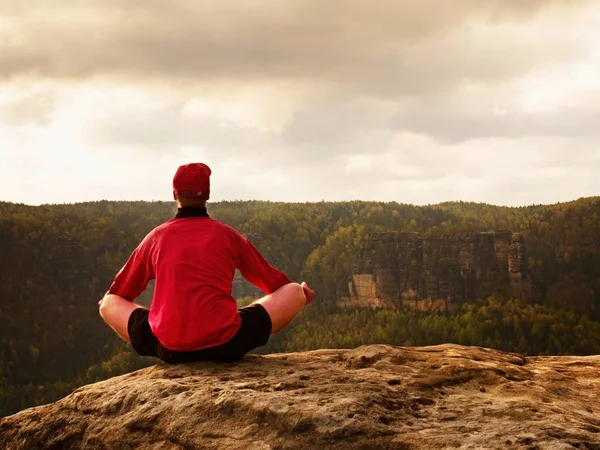 Uomo in cima alla montagna in posa yoga. Esercizio yoga sul bordo con una vista mozzafiato — Foto Stock