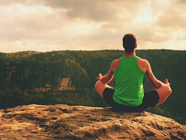 Man meditating in Lotus Pose on rocky cliff. Sportsman practicing Yoga on stone edge — Stock Photo, Image