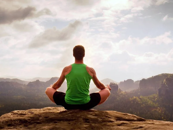 Man meditating in Lotus Pose on rocky cliff. Sportsman practicing Yoga on stone edge — Stock Photo, Image