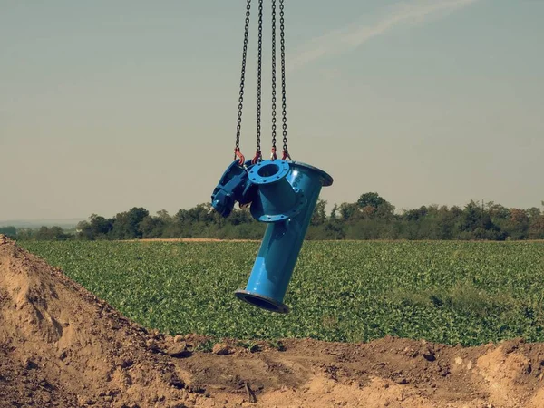 Crane lifting tube and gate valve within water pipeline building. New construction part — Stock Photo, Image