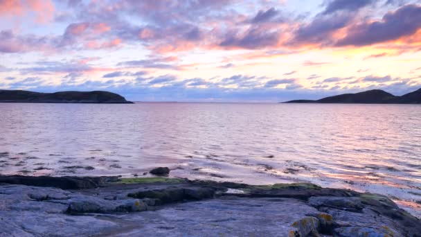 Auringonlasku Pohjanmeren yllä. Vesilevät uivat meren pinnalla vuoroveden aikaan. Henkeäsalpaava auringonlasku vuorten taustalla horisontissa — kuvapankkivideo