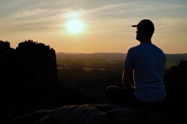 Beyzbol şapkası dağın zirvesinde olan adam. Kayalar silüeti.