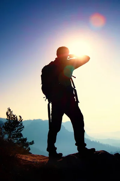 Touristen mit sportlichem Rucksack stehen auf einem felsigen Aussichtspunkt und blicken ins neblige Tal. sonniger nebliger Tagesanbruch in den felsigen Bergen. — Stockfoto