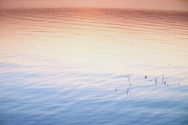 Hermoso amanecer de otoño o puesta de sol con Reflexión en el nivel del agua del lago. Ondas suaves . — Foto de Stock