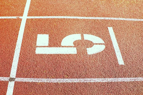 Az ötödik. Nagy fehér zeneszám piros gumi versenypályára. Finom szerkezetű futás futamok atlétikai stadionban. — Stock Fotó