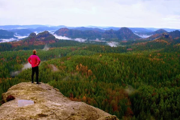 Läufer in rosa Jacke und hellschwarzer Hose. kurze Ingwerhaare im Visier. Müder Sportler rastet auf Pfad in Felsen aus. — Stockfoto