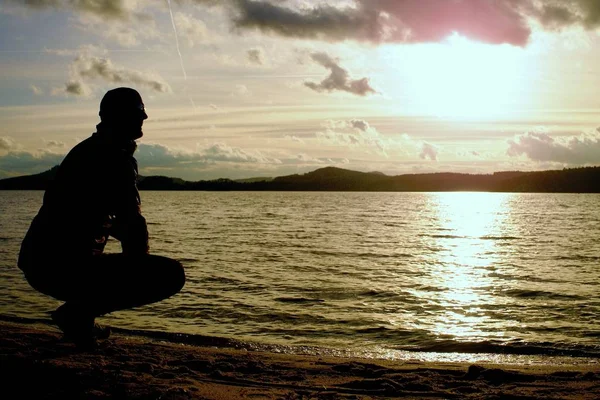 Man stand near beach looking at sunset, peaceful water level