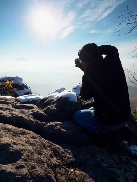 Профессиональный фотограф фотографирует с зеркальной камерой и штативом на снежной вершине . — стоковое фото