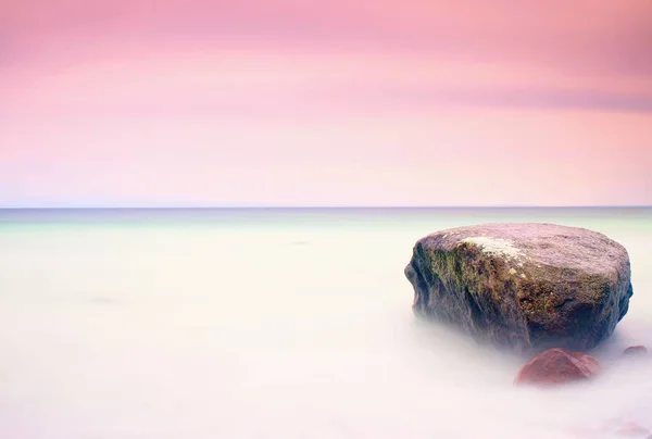 Romantickou atmosféru v klidné dopoledne na moři. Velké balvany vyčnívající z hladké vlnité moře. Růžový obzor — Stock fotografie