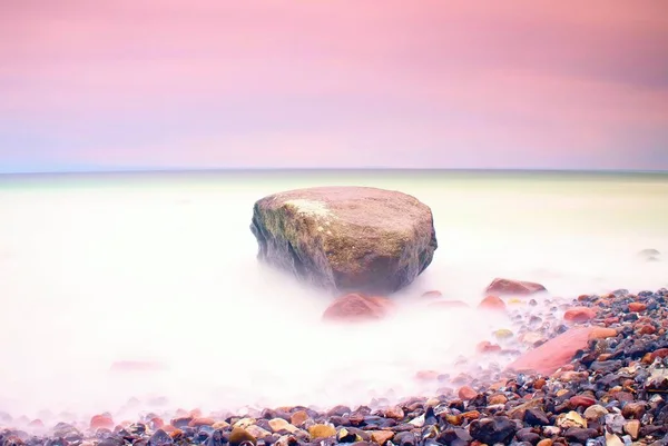 Ambiente romántico en la mañana tranquila en el mar. Grandes rocas que sobresalen del suave mar ondulado. Horizonte rosa — Foto de Stock