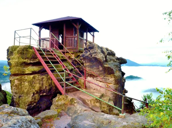 Scena nebbiosa pesante autunnale. Cabina in legno sulla cima principale della roccia — Foto Stock