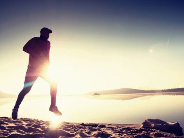 İnce genç fitness adam plaj, tropikal iz runner runner. Neşeli sporcu kumsalda koşmak