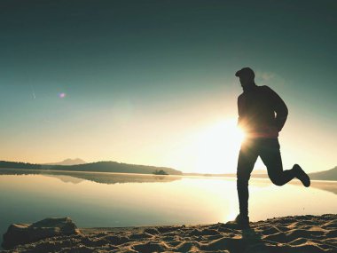  egzersiz ve göl kumsalda güneş doğarken uzanan bir adam. Sağlıklı bir yaşam tarzı. Yalnız genç fitness adam egzersiz sabah kumsalda